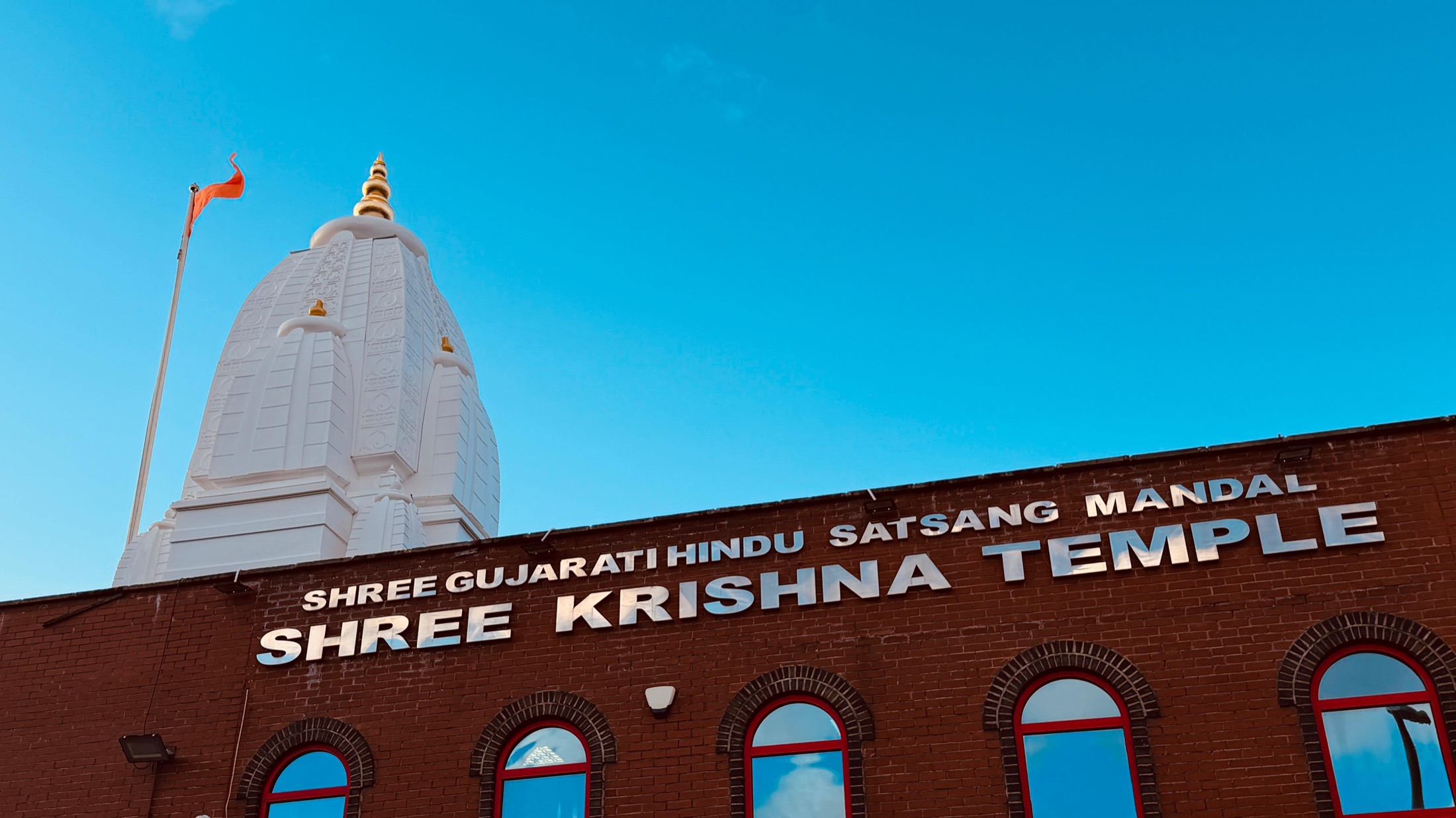 Shree Krishna Temple on Harnall Lane West: the brick hall with the temple's name above arched windows and the white shikhar behind
